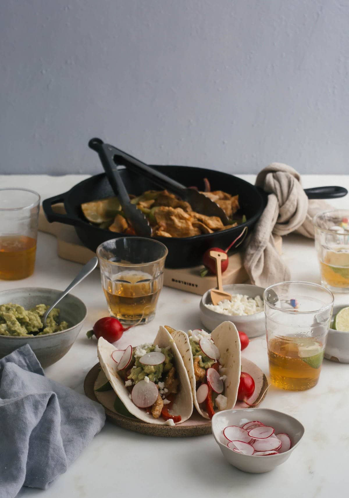 Side view of chicken fajitas on a plate with glasses of beer near by. 