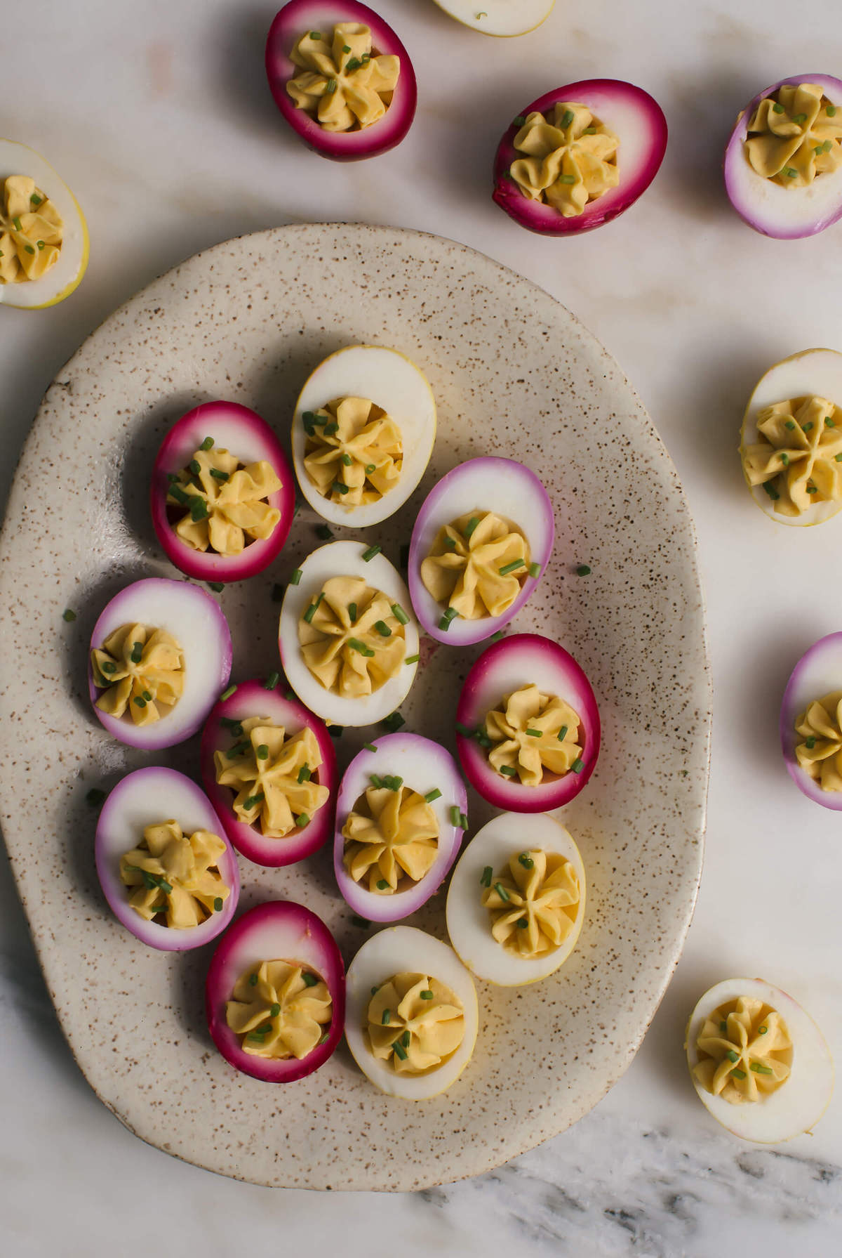 Naturally pickled deviled eggs on a platter topped with chives.