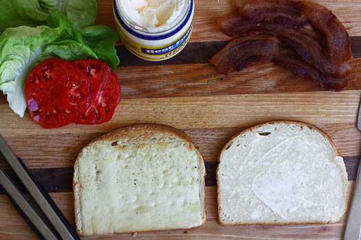 Assembling the Spanglish sandwich. Lettuce, tomato, bacon on bread. 