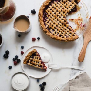 Slice of mixed berry pie on a plate with whipped cream.