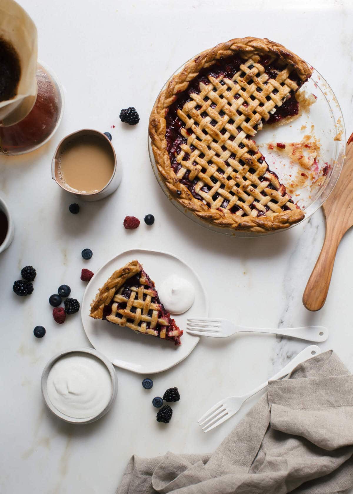 Slice of mixed berry pie on a plate with whipped cream.