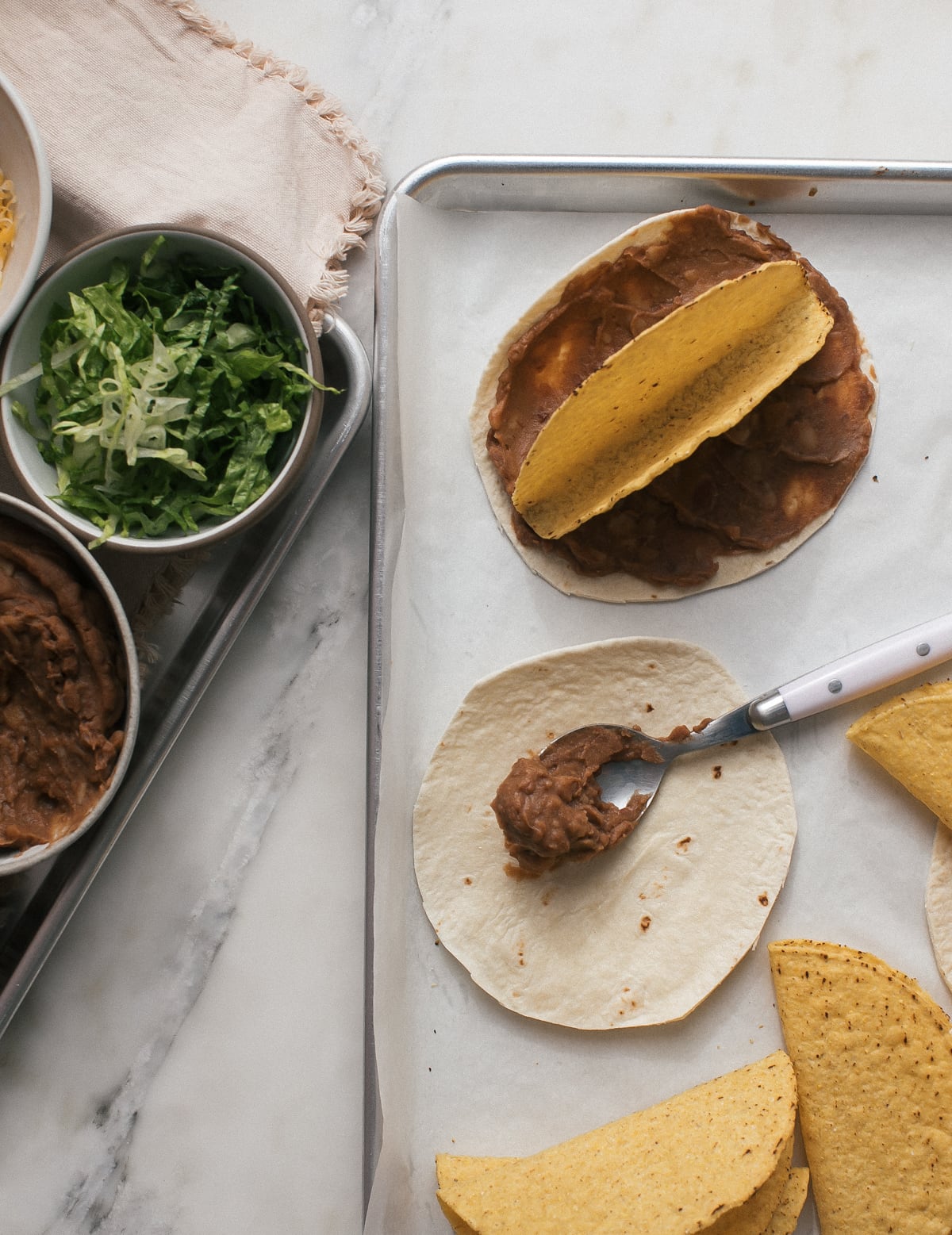 A spoonful of refried beans on a flour tortilla. 