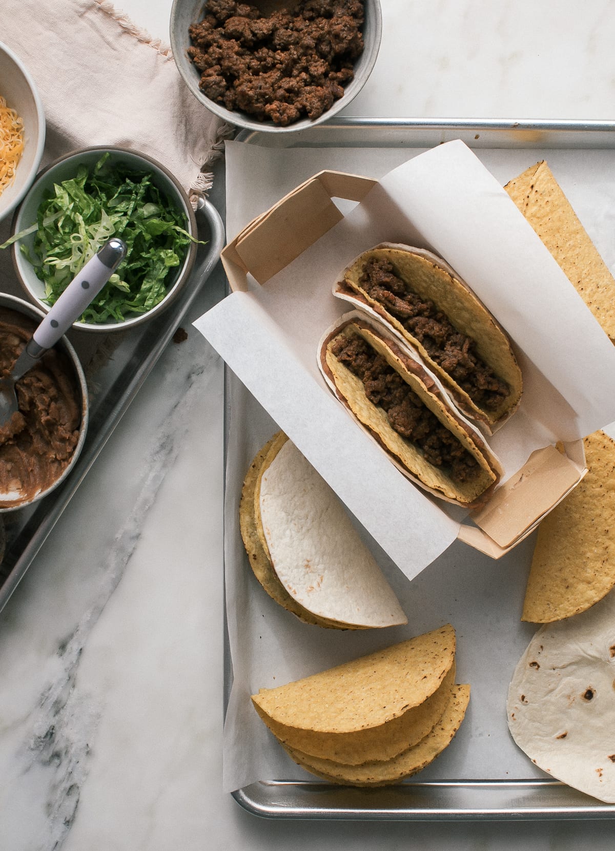 Corn taco shells filled with ground beef wrapped in refried beans and flour tortillas.