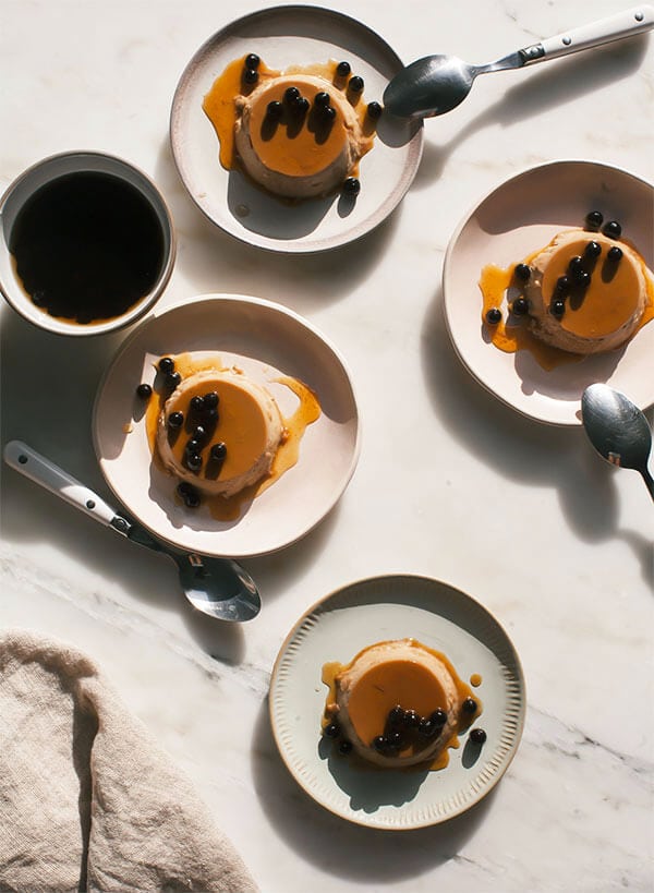 Milk tea flan on plates topped with boba and caramel sauce.