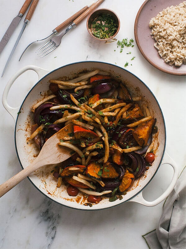 Squash saltado in a skillet with a wooden spoon.