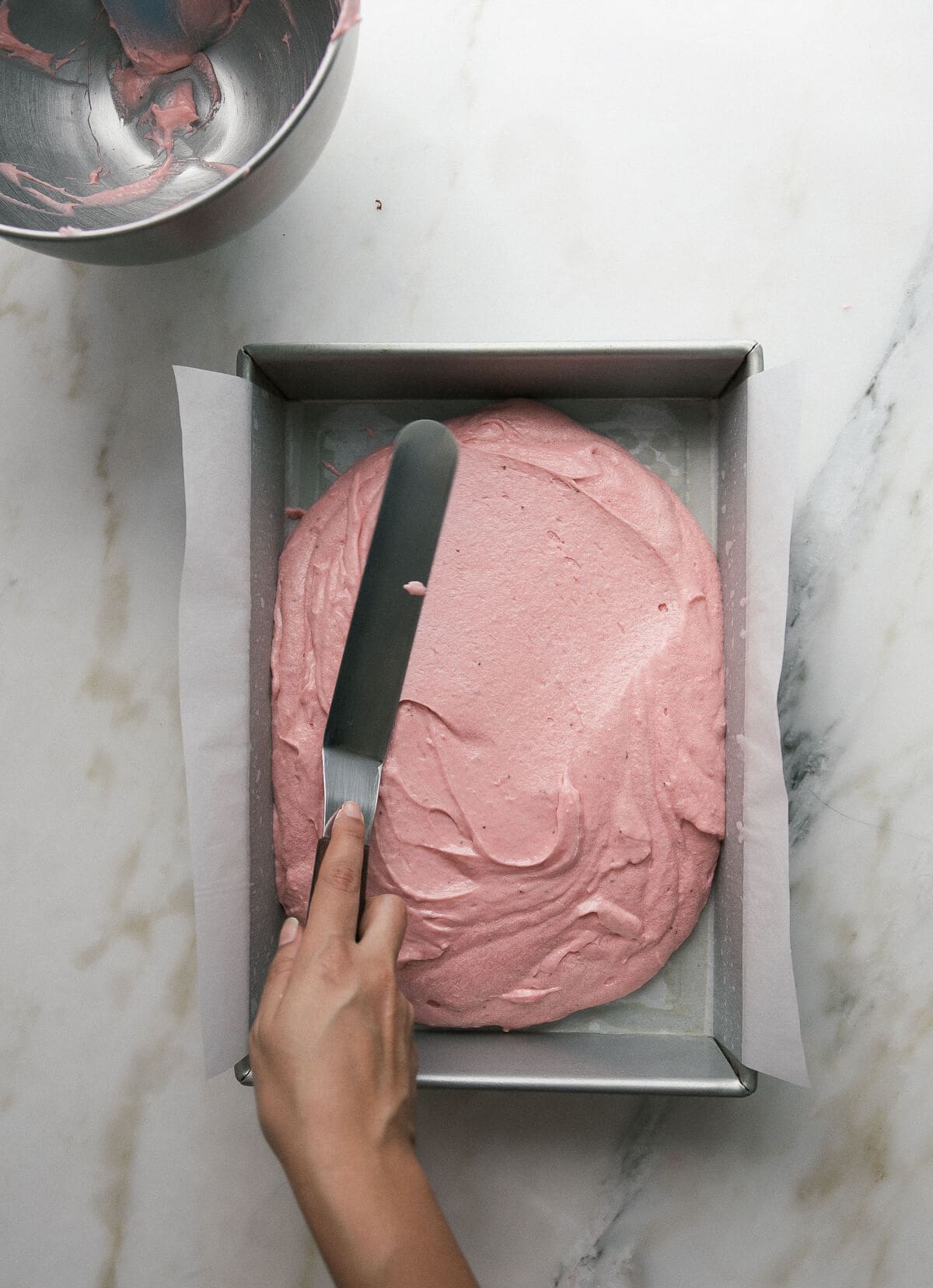 Cake batter being spread out in a sheet pan with an offset spatula. 