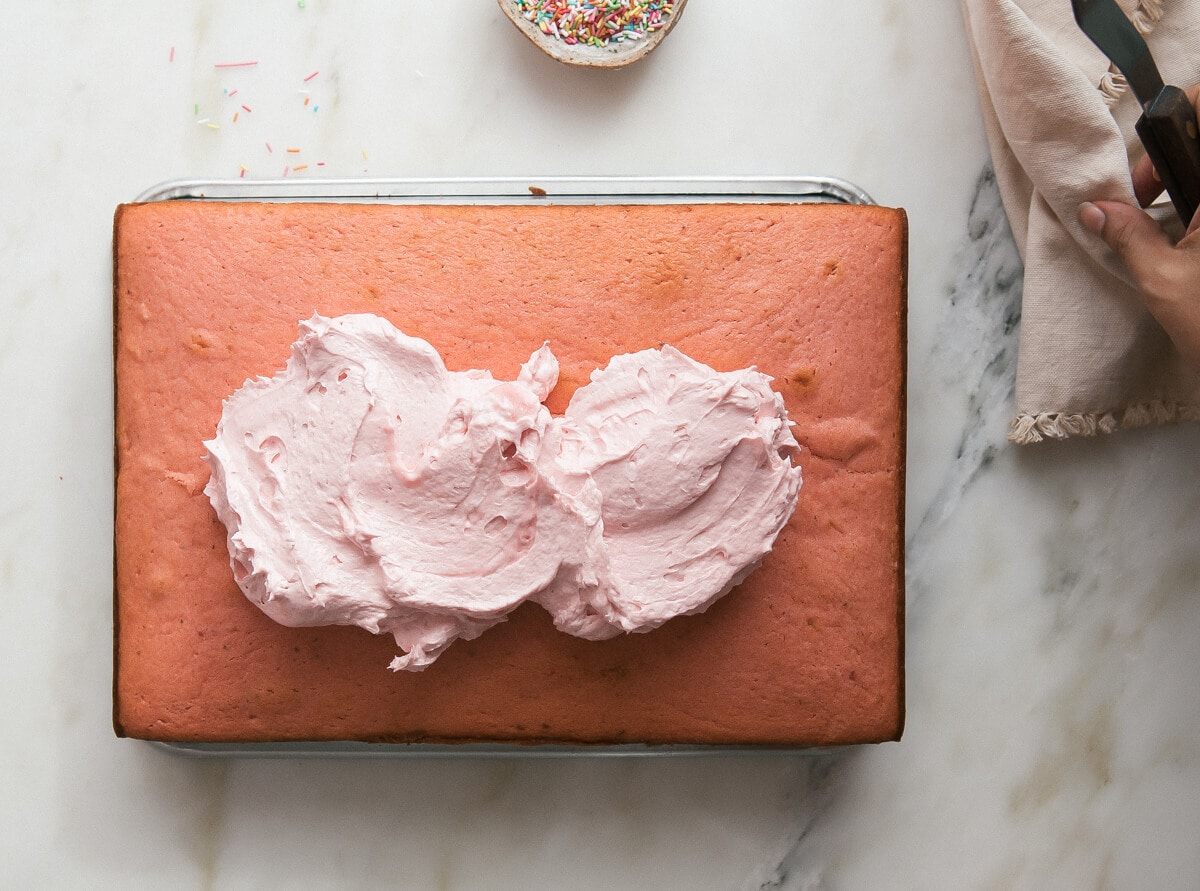 A baked strawberry cake topped with dollops of frosting. 