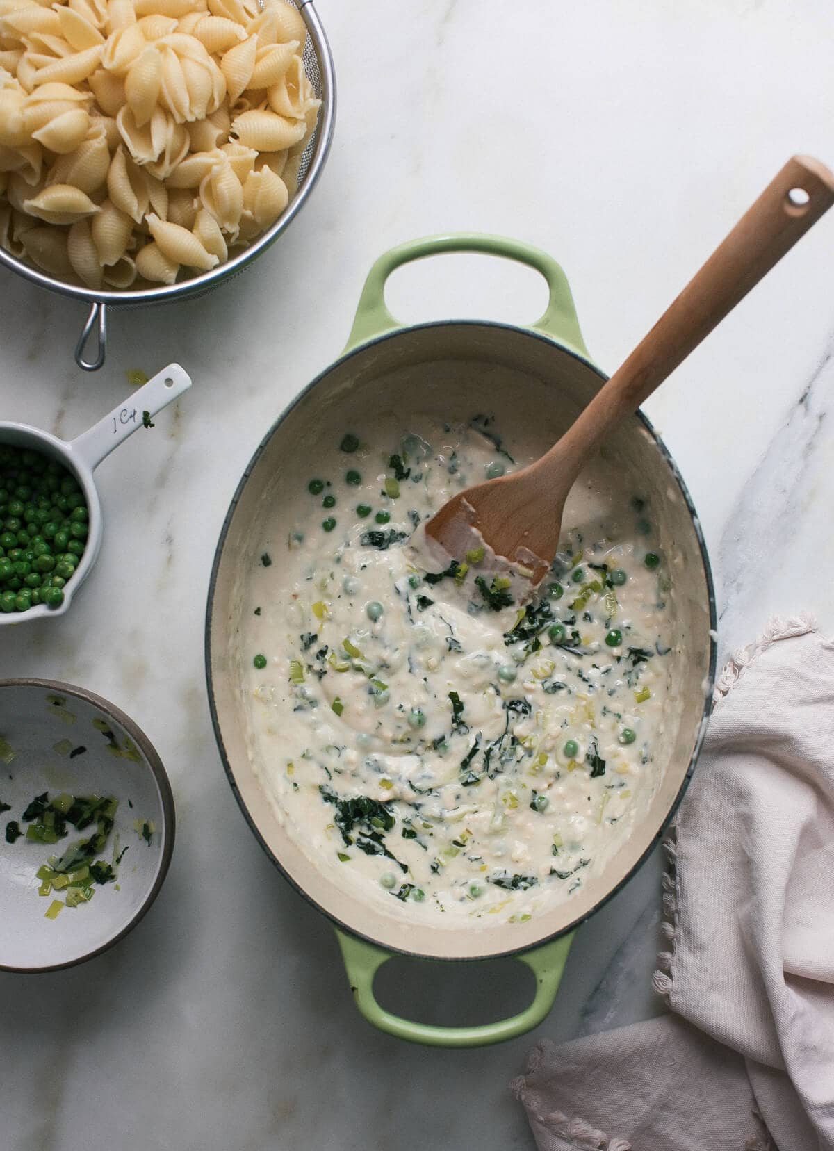 Cheese sauce mixed with cooked spring vegetables in a pot.