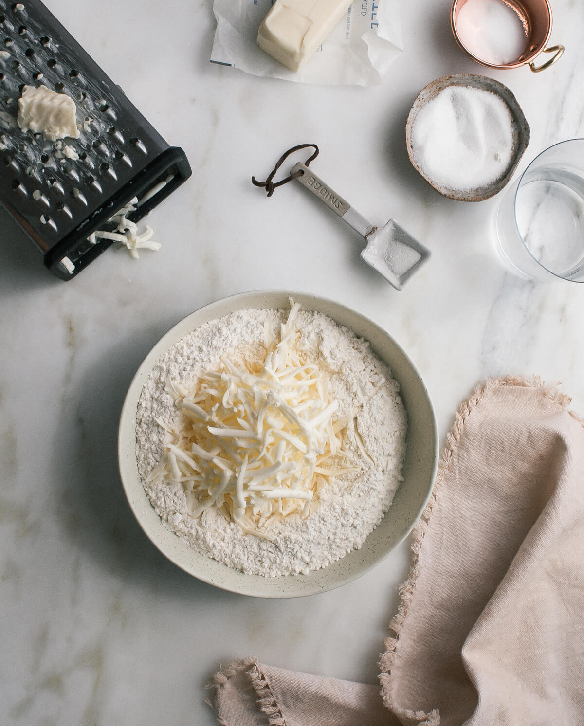 A bowl of flour with grated butter on top.