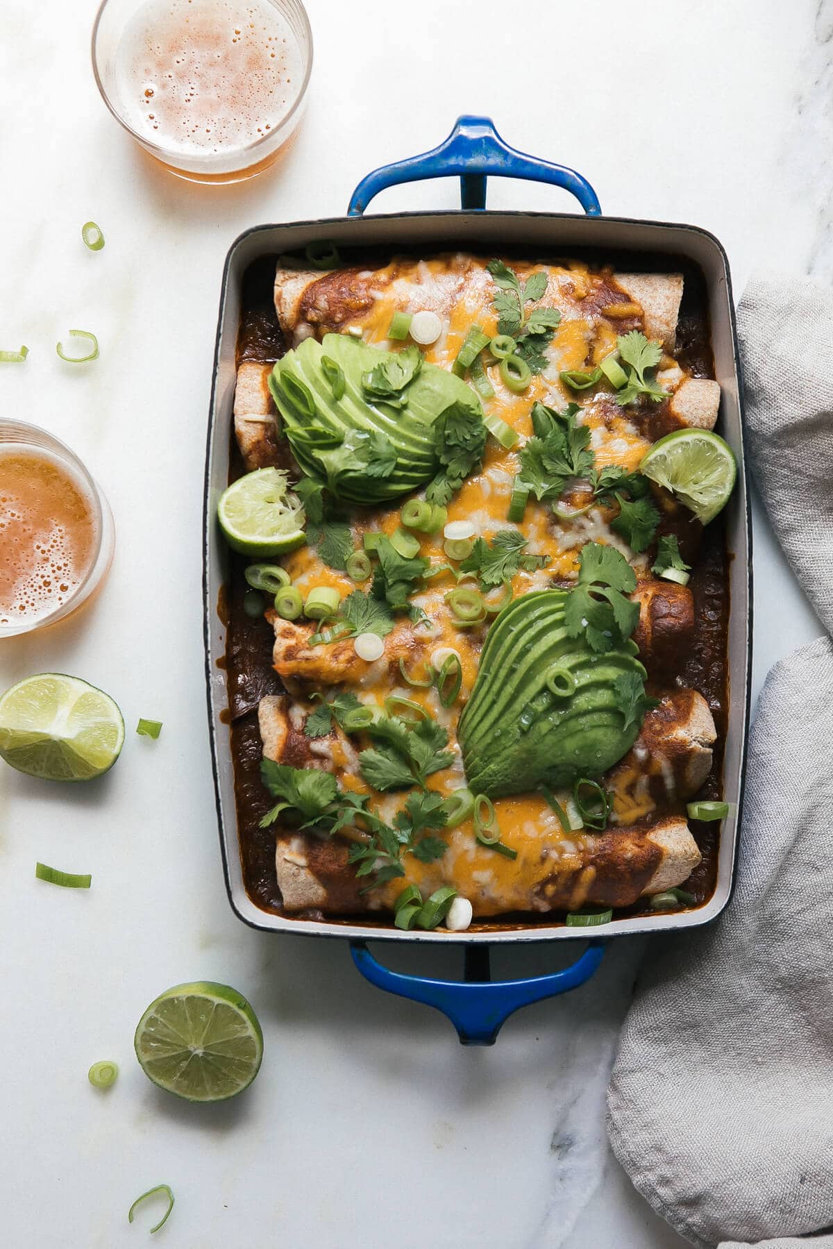 Enchiladas in a baking dish with toppings.