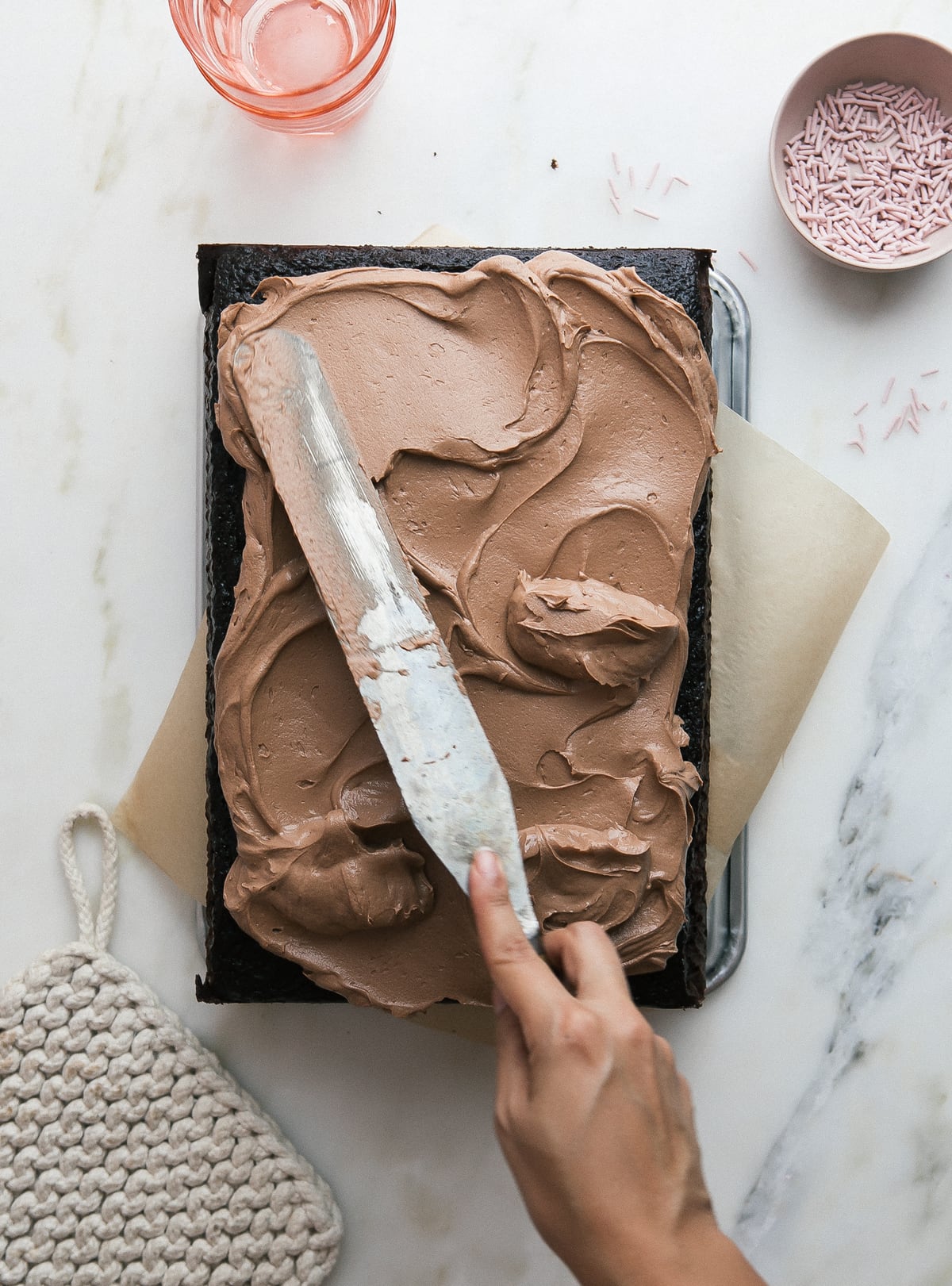 Overhead image of someone frosting a cake with an offset spatula. 