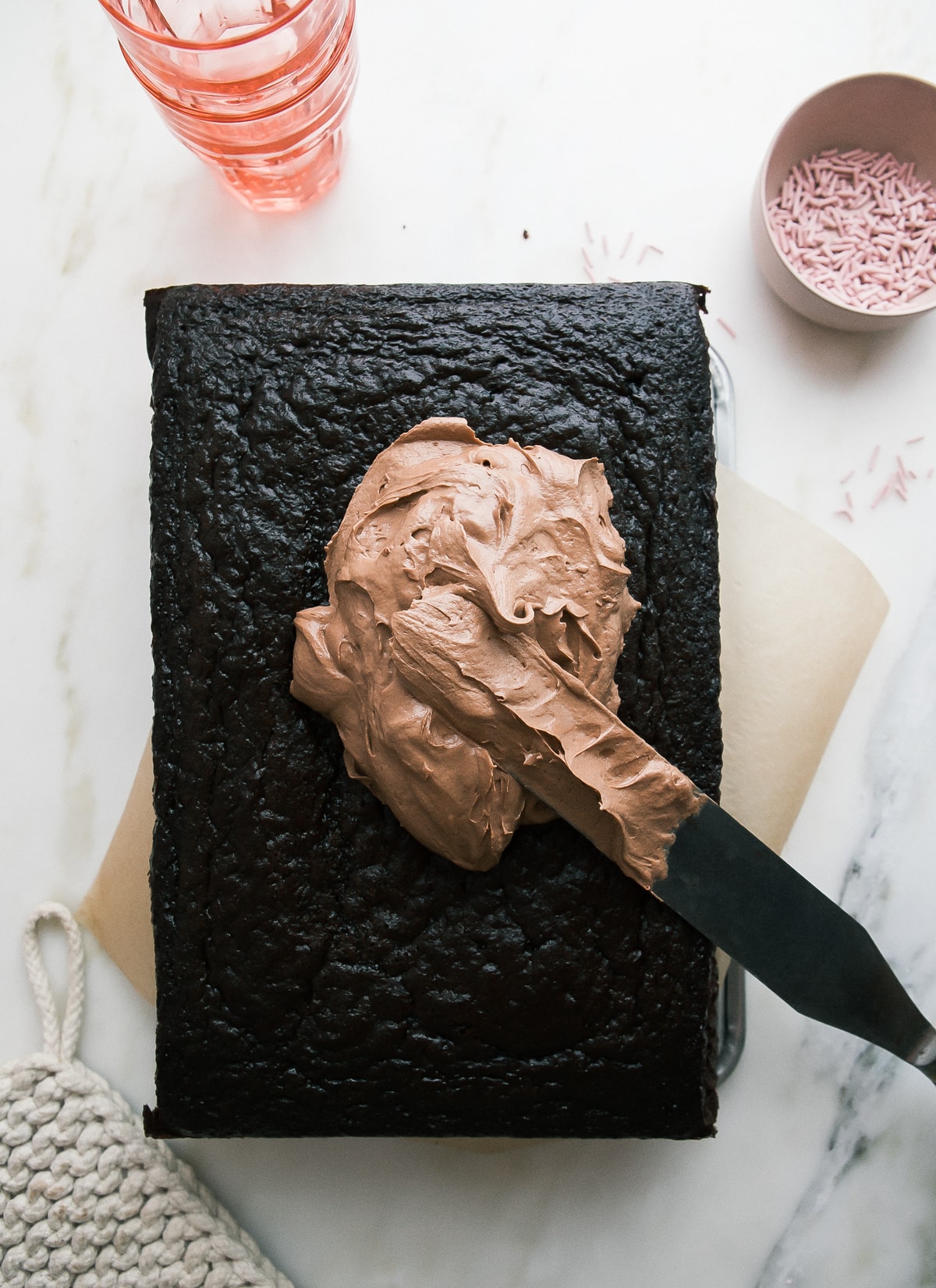 Frosting spooned over a chocolate cake.