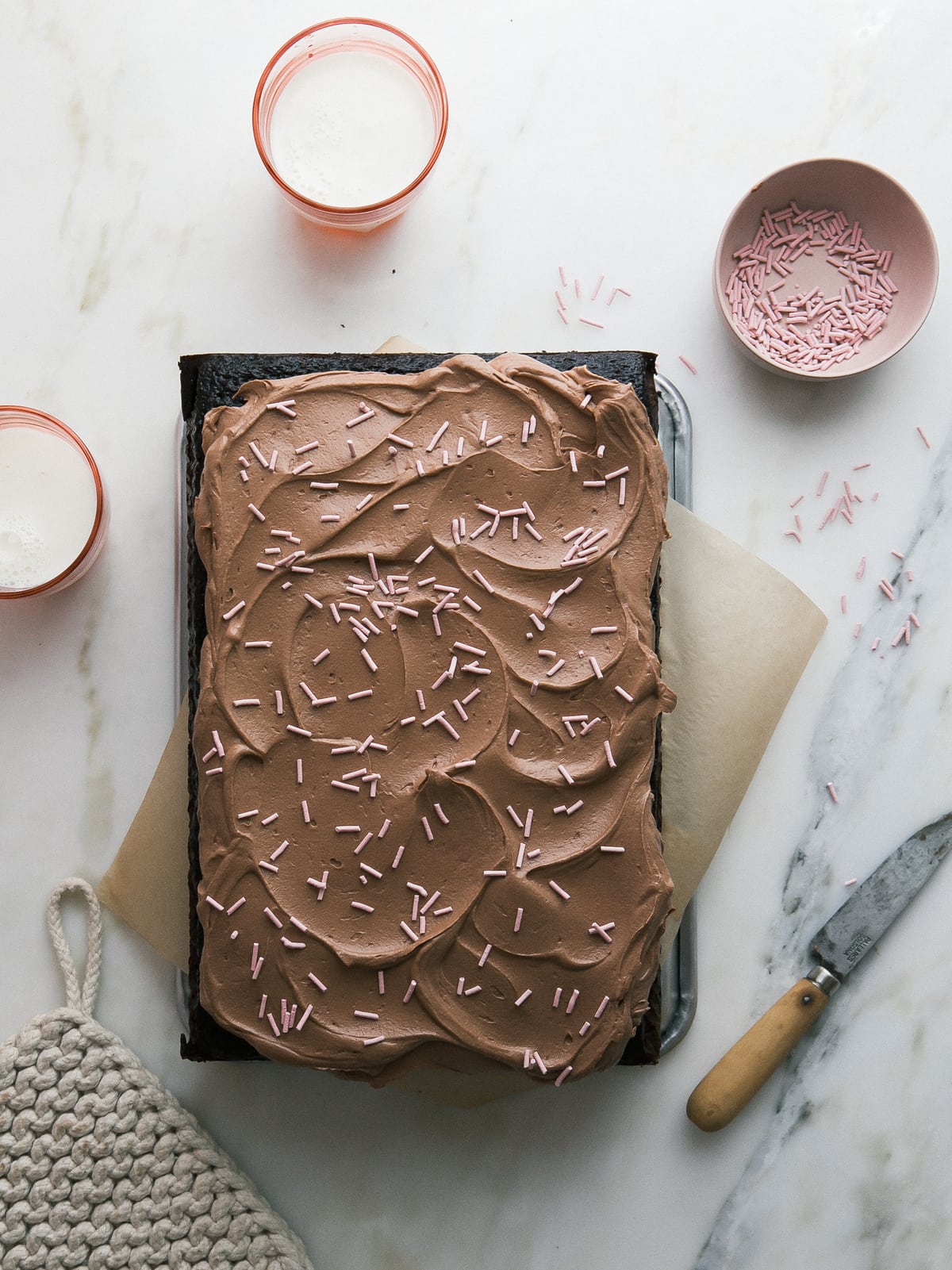 Overhead view of a frosted one bowl chocolate cake with sprinkles.