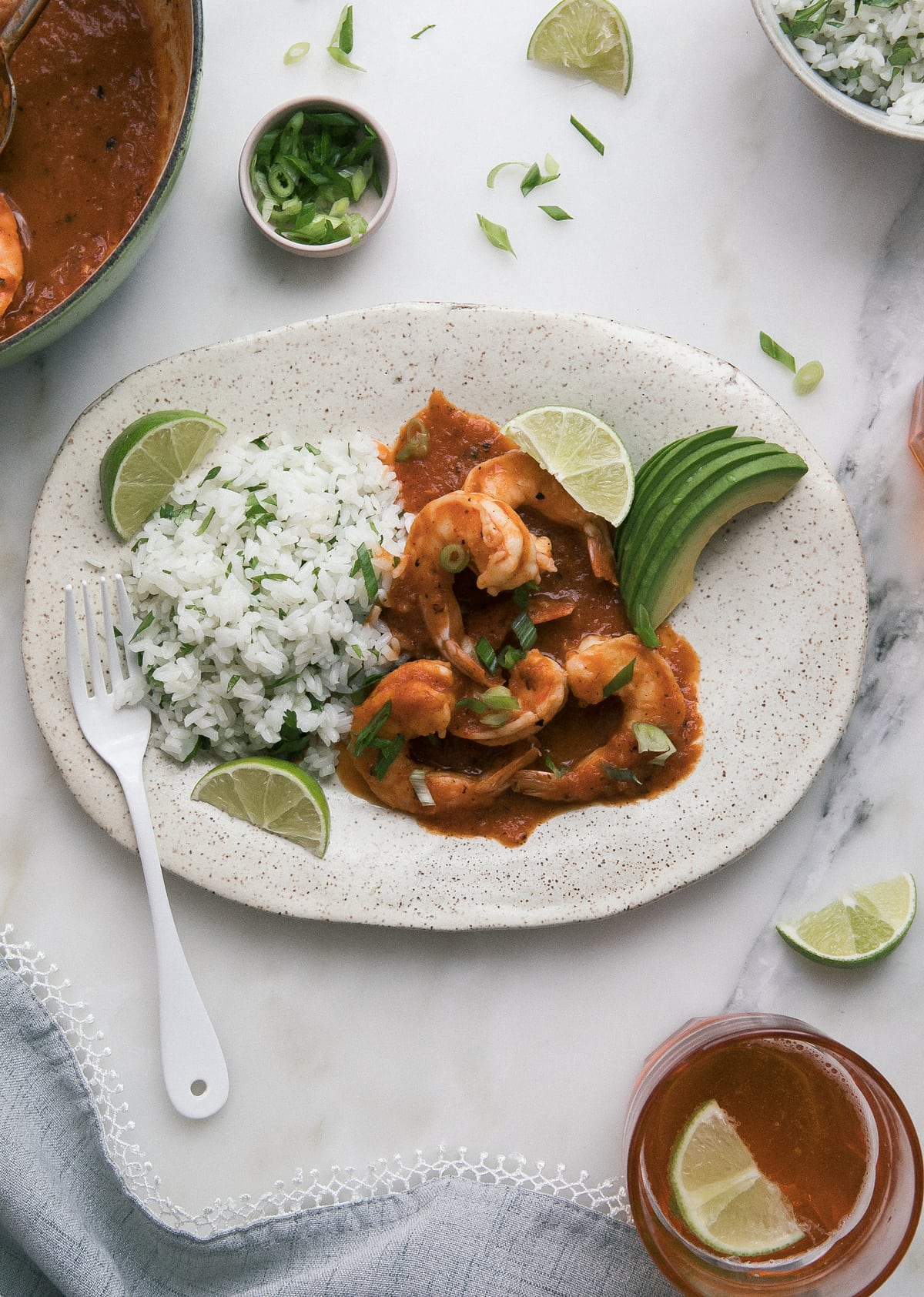 Close up image of camarones a la diabla on a plate with lime wedges.