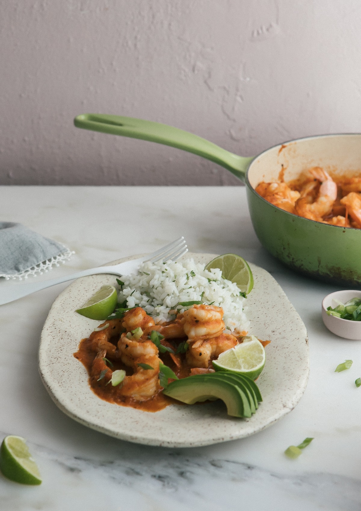 3/4 view of Camarones a la Diabla on a plate with rice and lime wedges.