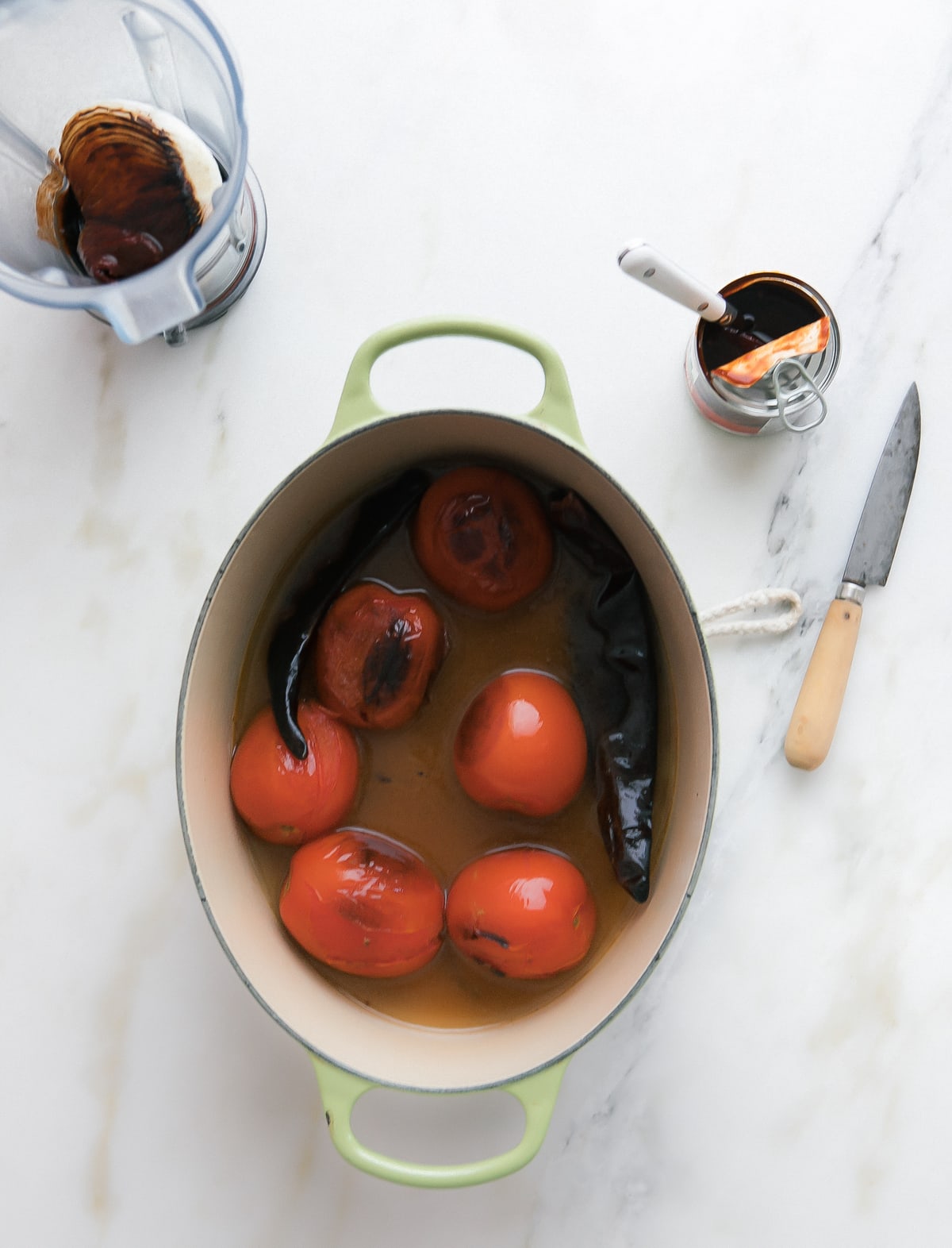 Blistered tomatoes and chiles in water inside a dutch oven. 