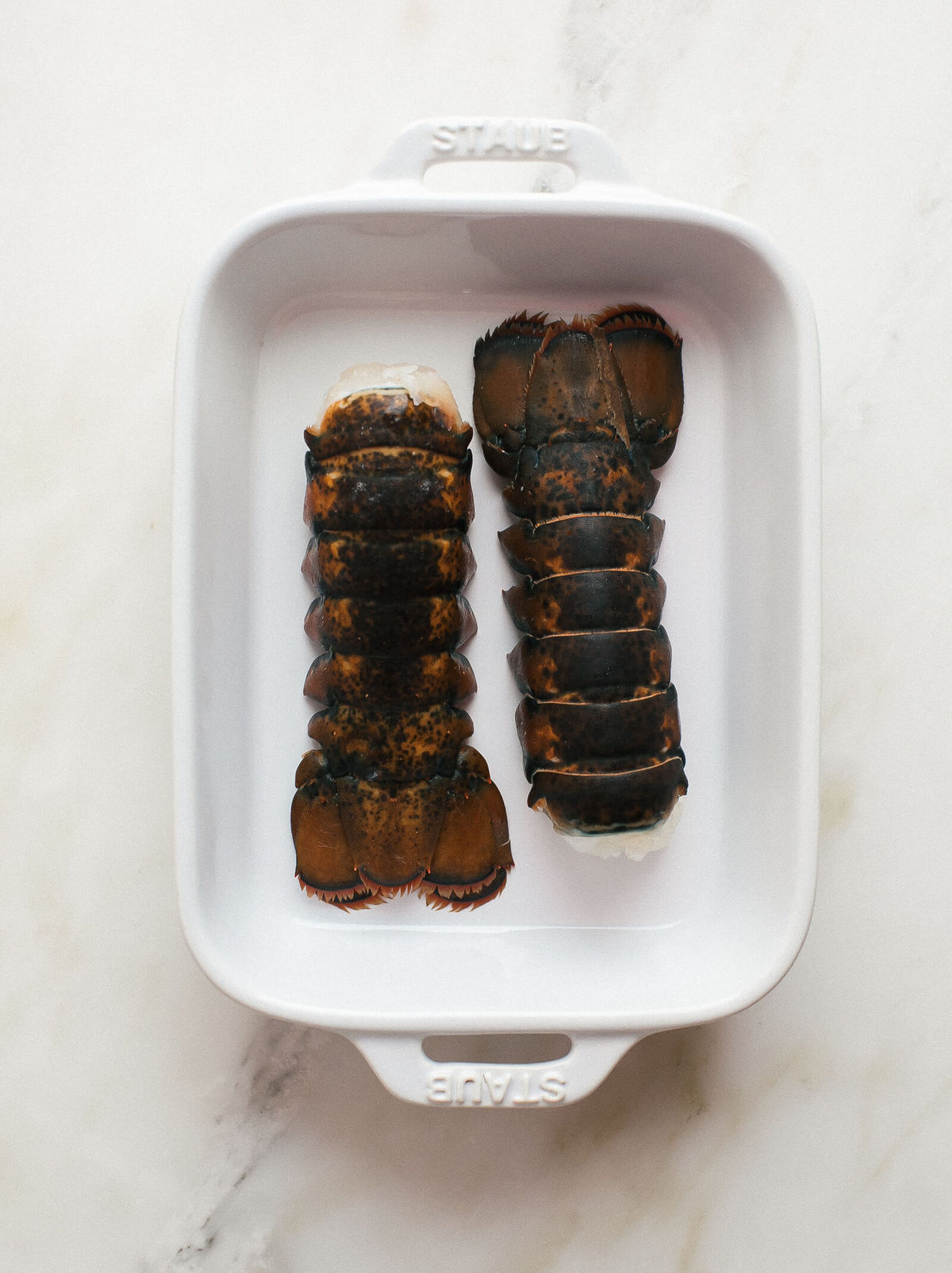 Two lobster tails in a baking dish.