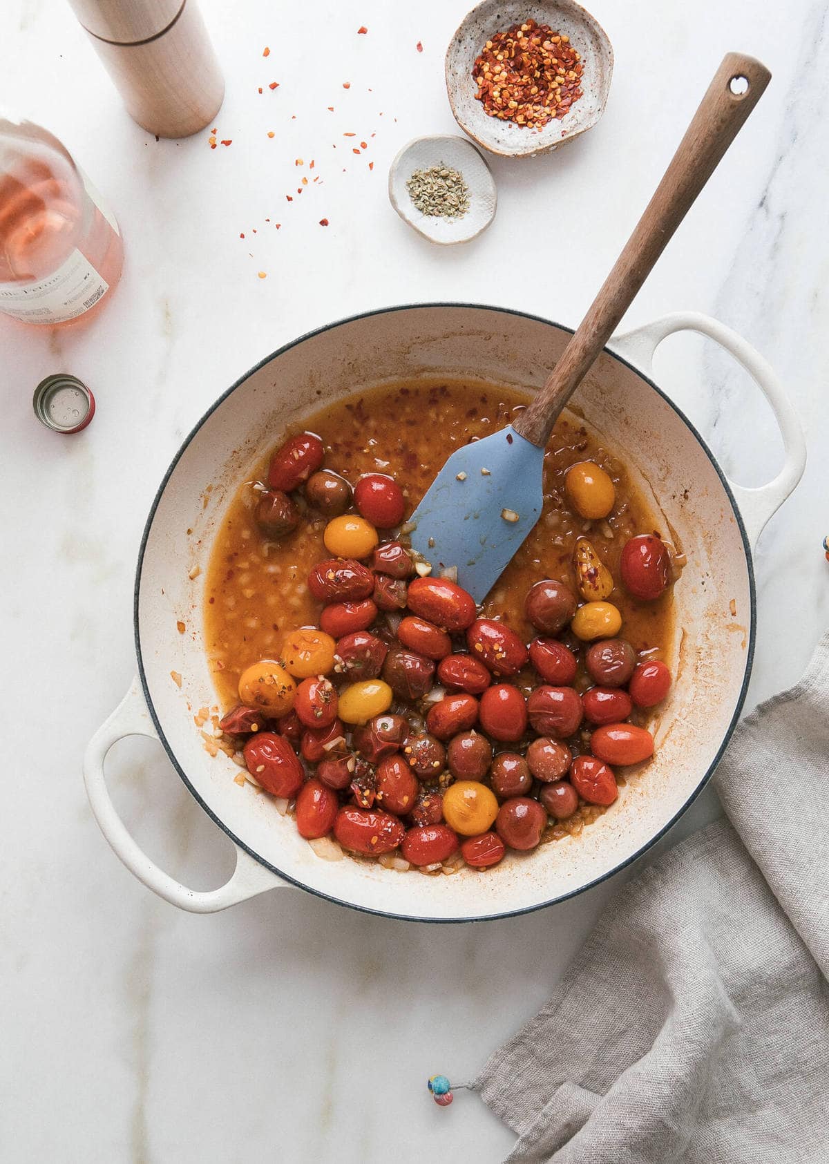 Blistered cherry tomatoes in a pot with a spatula.