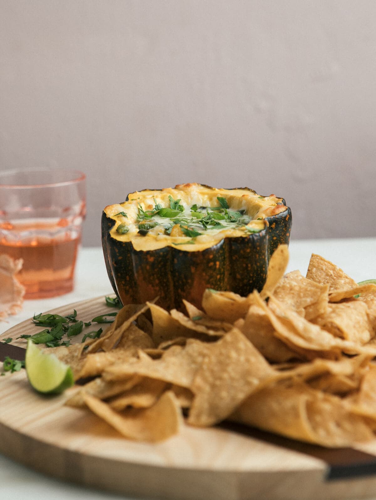 Side view of a squash stuffed with cheese with tortilla chips on a serving platter.