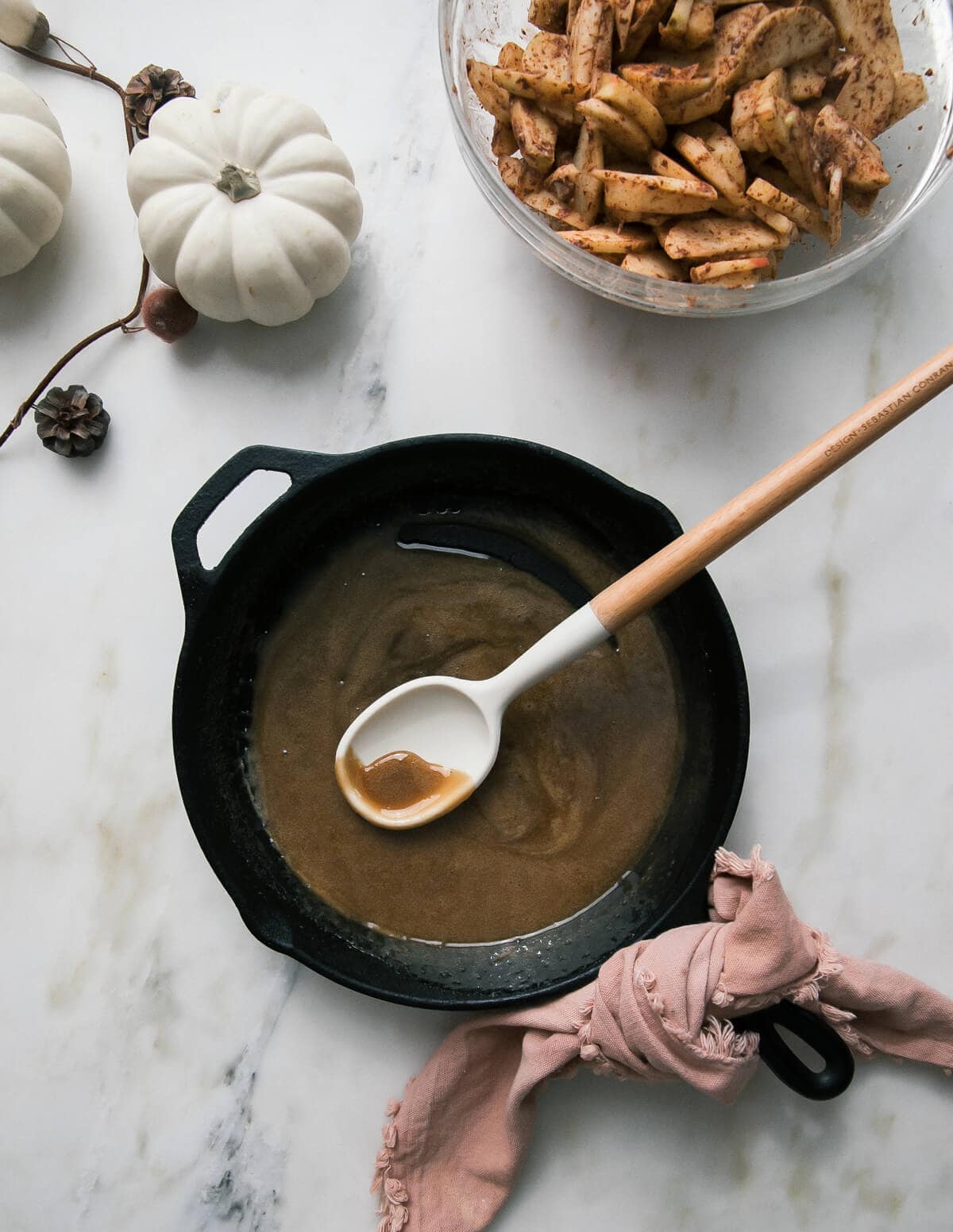 A cast iron skillet with butterscotch and apples on the side. 