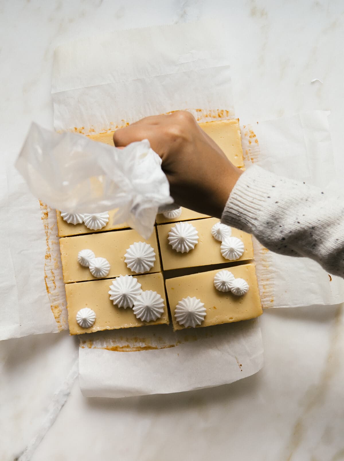 Overhead image of meringue topping being piped onto custard bars. 