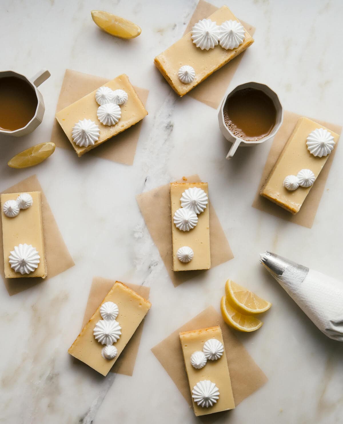 Pie de limon cookie bars topped with meringue topping on a counter with lemon slices and coffee.