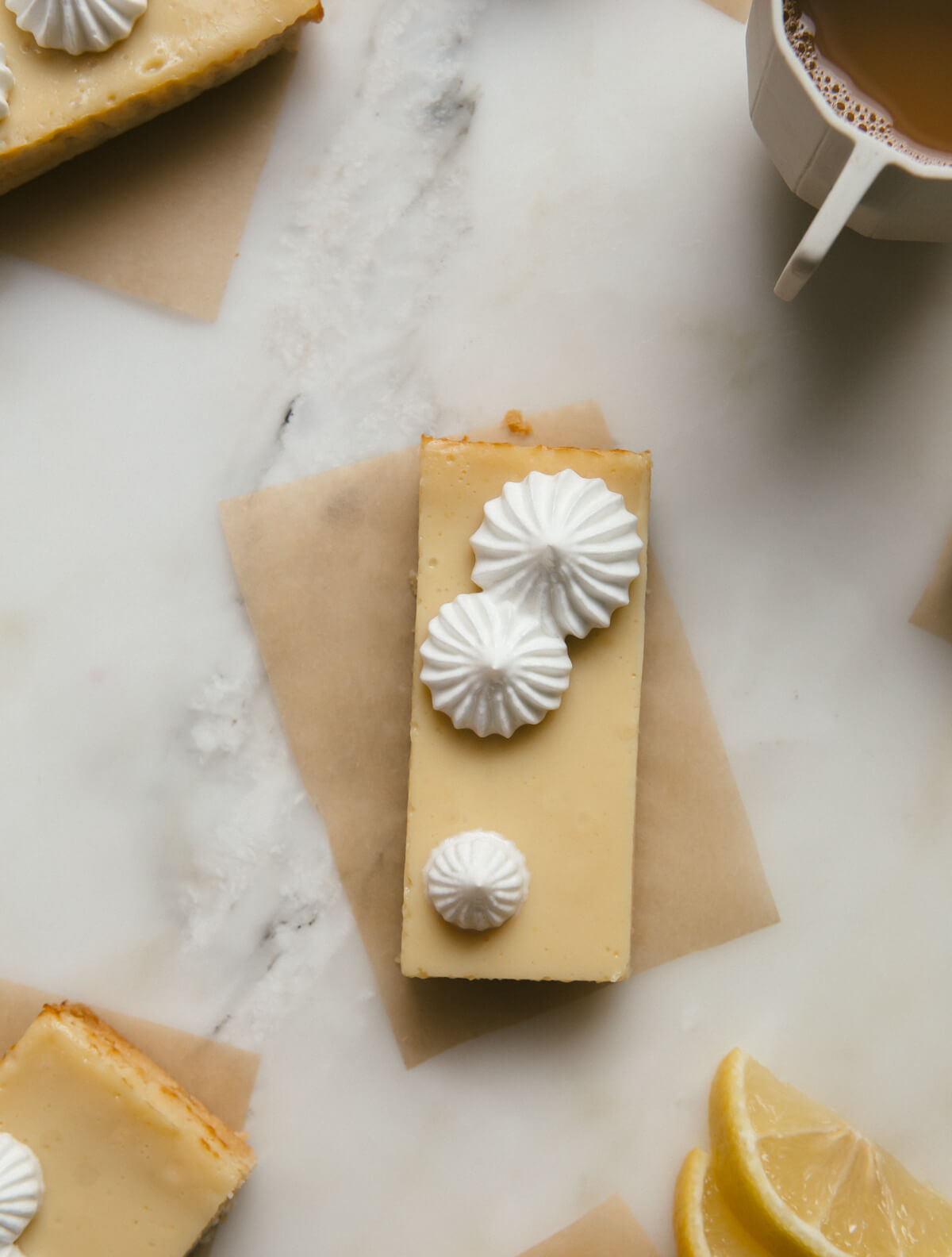 Overhead image of pie de limon bars on parchment paper with lemon slices nearby.