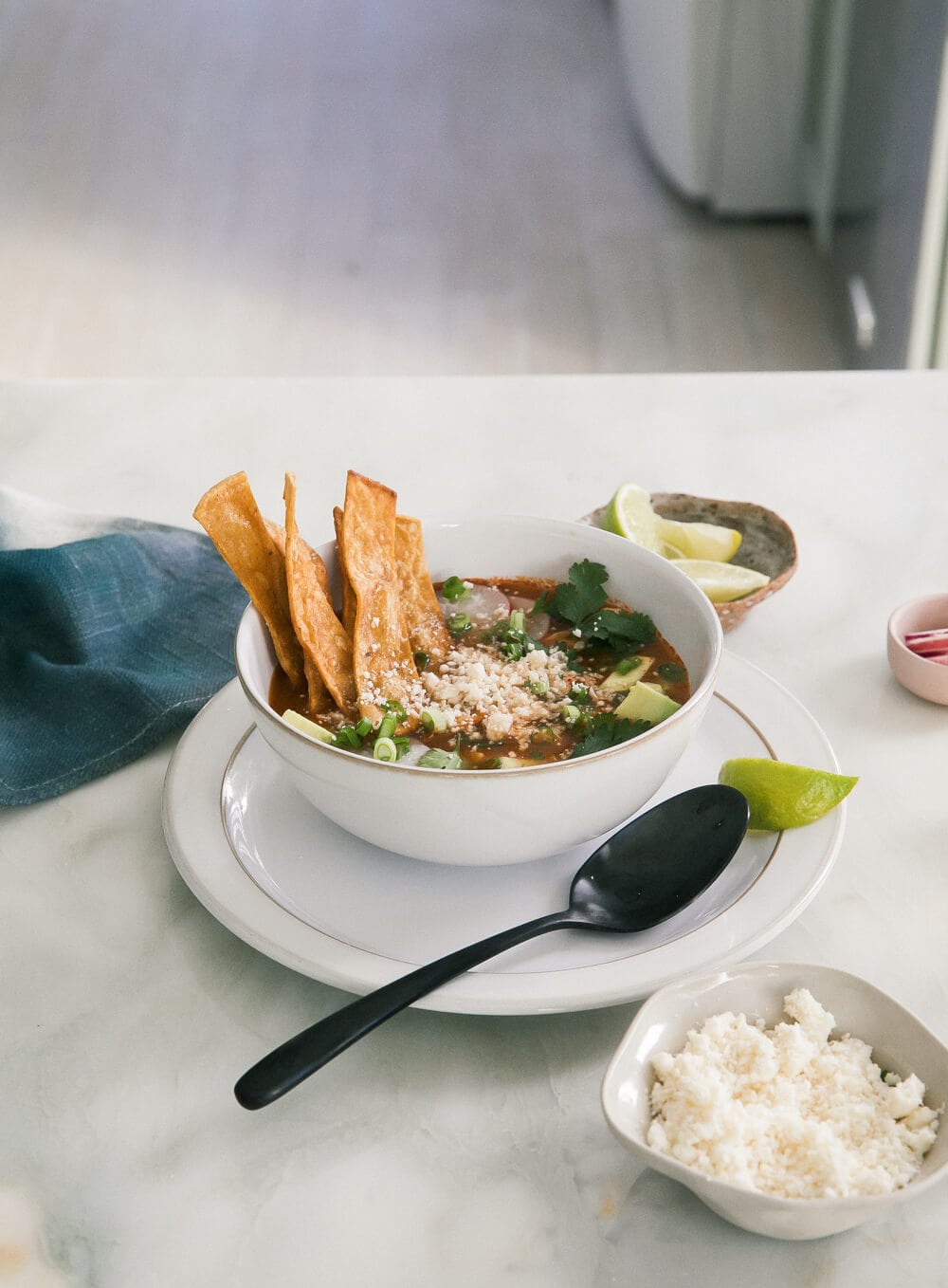 3/4 image of enchilada chicken tortilla soup in a bowl with tortilla strips.