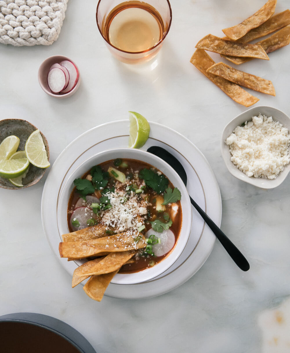 Soup in a bowl with a spoon and toppings on a counter.