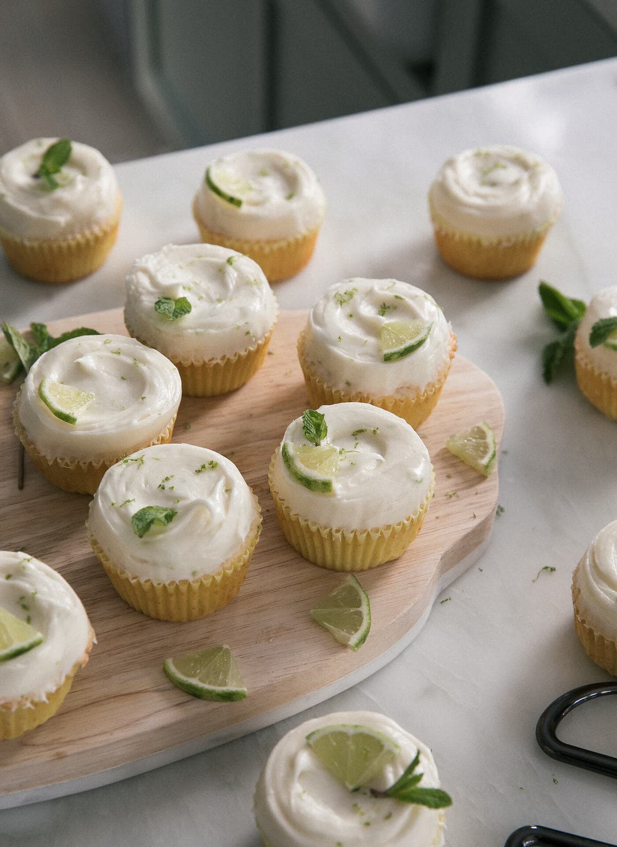 Mojito cupcakes on a cutting board with limes slices. 