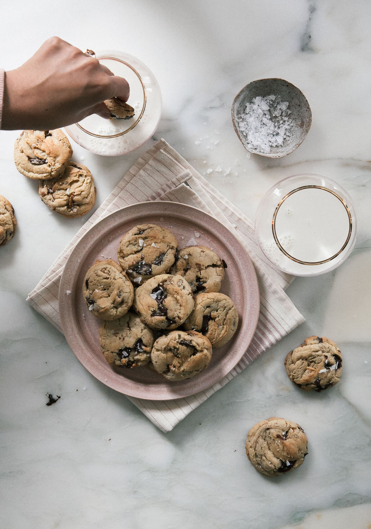 Cookies on a plate with glasses of milk.