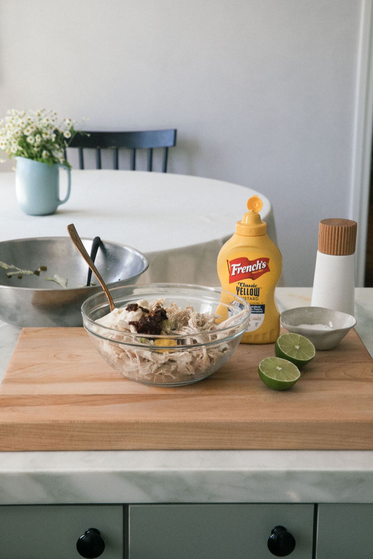 Chicken being mixed with chipotles and mustard in a bowl. 