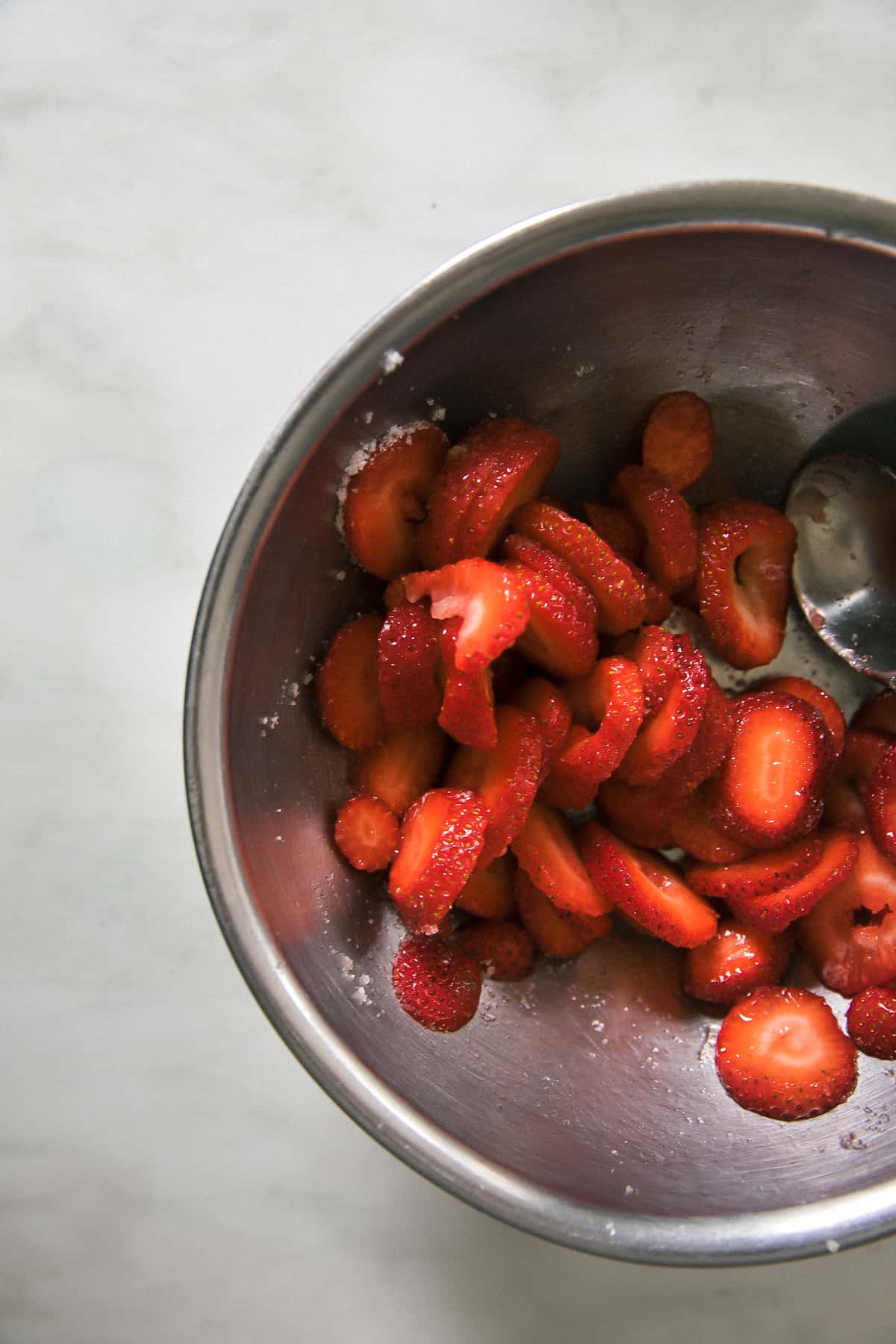 Strawberries in a bowl being macerated. 