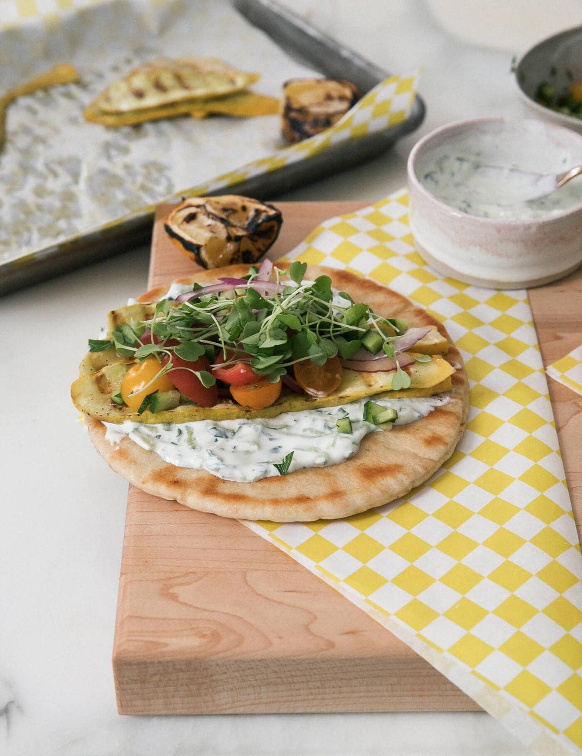 Pita bread topped with yogurt sauce, quash and microgreens.
