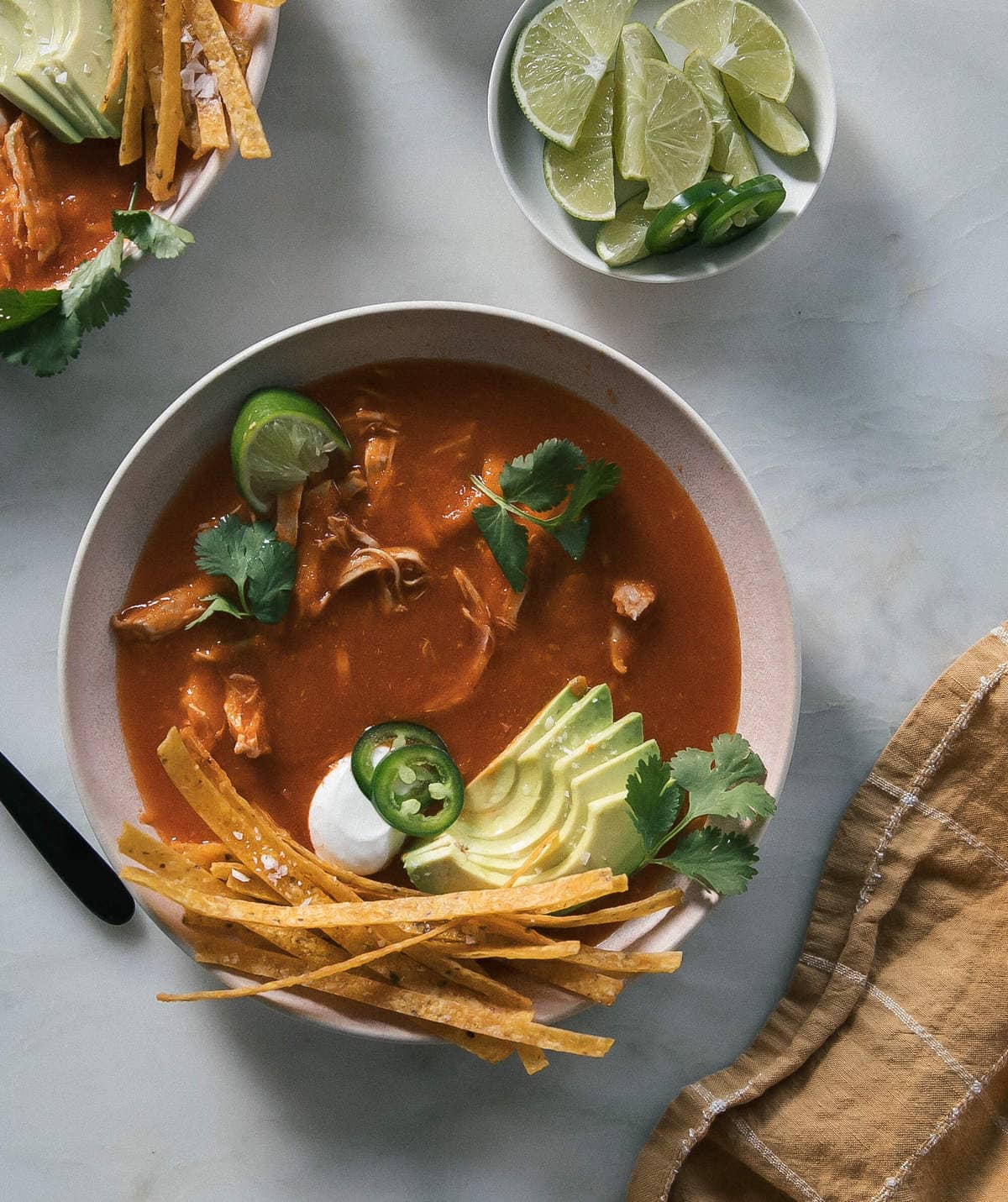 Overhead image of tortilla soup in a bowl with toppings.