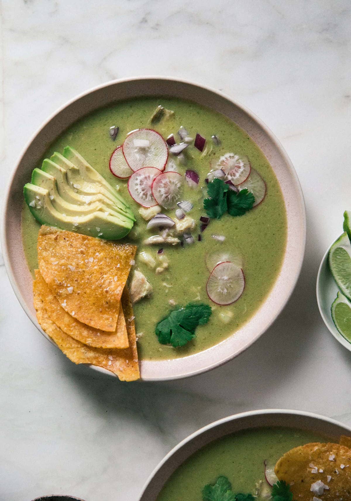 Tortilla chips with avocado, radishes and hominy in a bowl. 