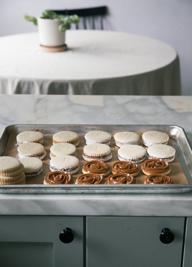 Alfajores being assembled on a baking sheet. 