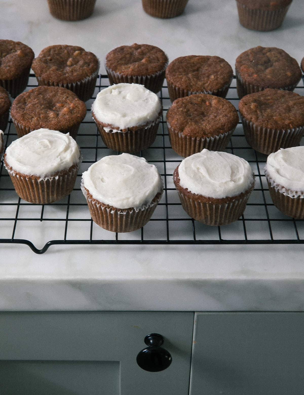 Cupcakes being decorated with first layer of frosting. 