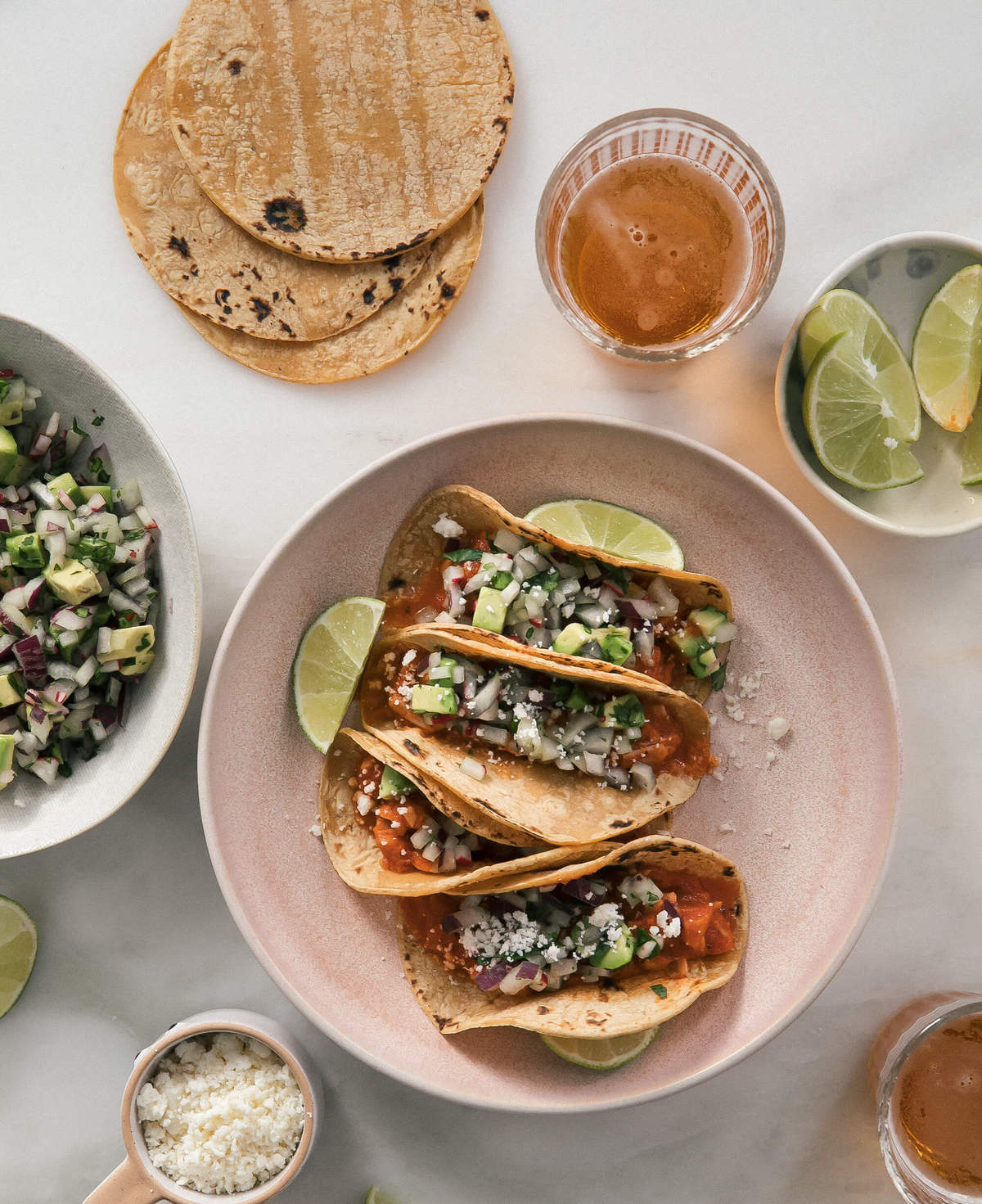 Jackfruit tinga tacos on a plate with taco toppings in bowls nearby.