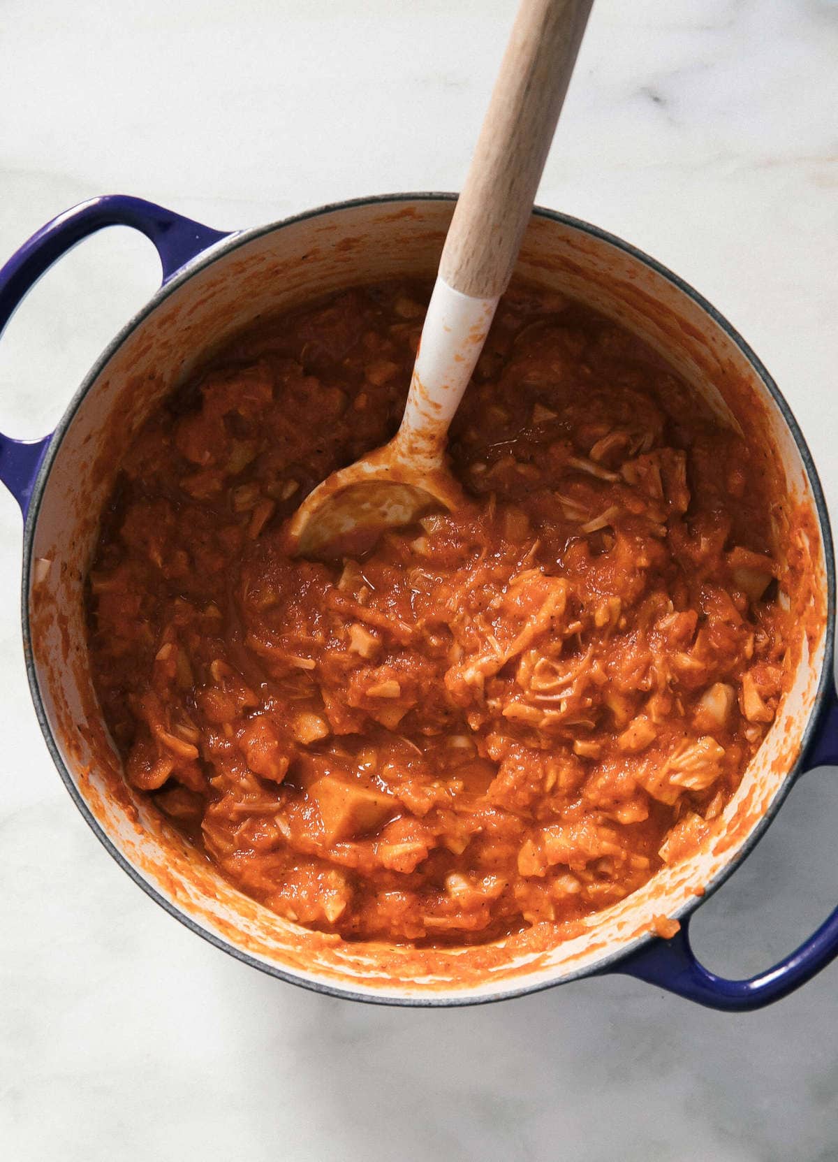 Jackfruit tinga sauce in a pot with a spoon.