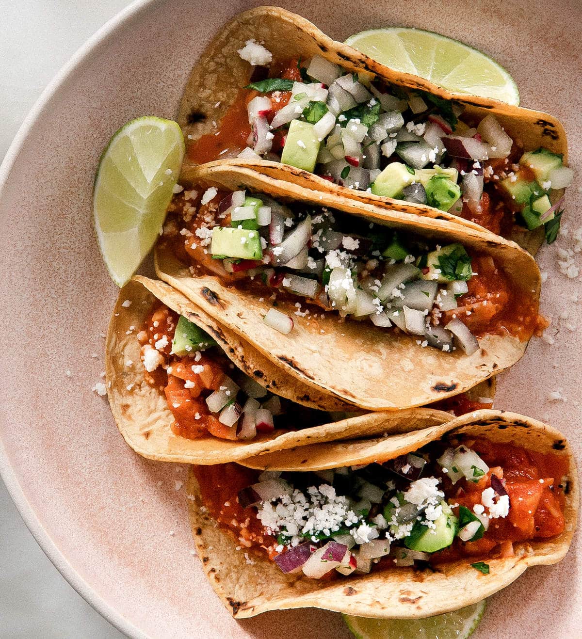 Close up image of vegetarian tacos on a plate topped with cheese.