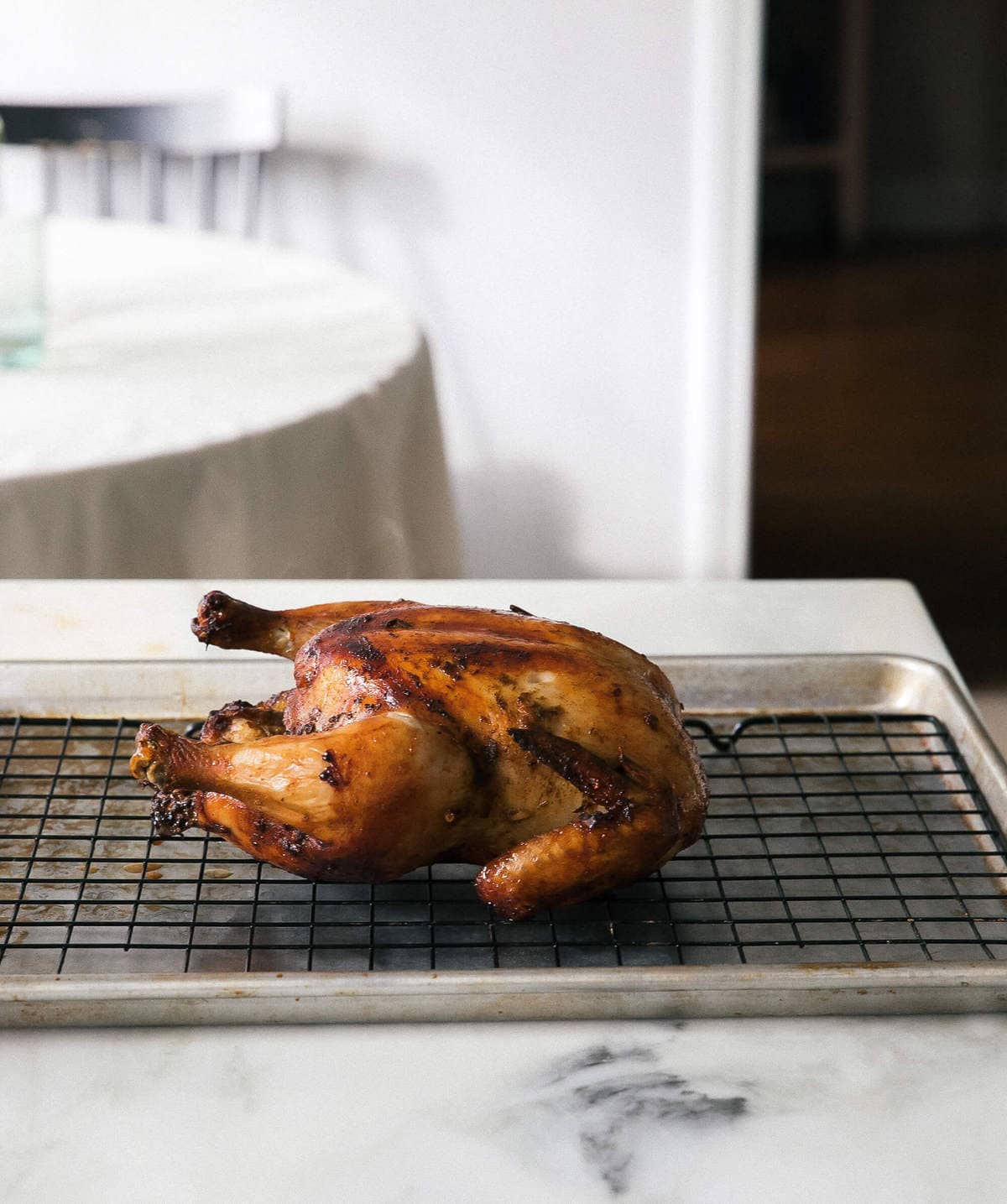 Roasted chicken on baking sheet resting.