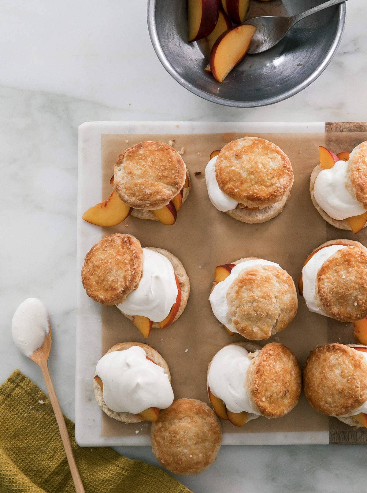 Peach Shortcakes on a cutting board with whipped cream. 