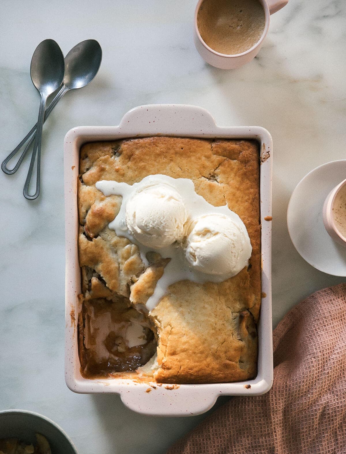 Apple cobbler with two scoops of vanilla ice cream and a spoonful of cobbler removed.