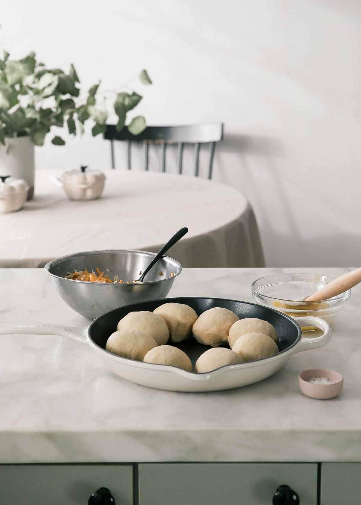 Process image of pretzel dough in a skillet with ingredients all around.