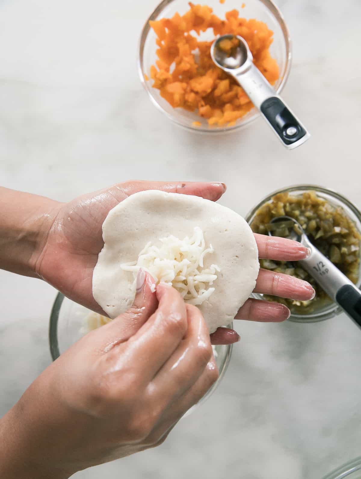 Pupusas being filled with cheese