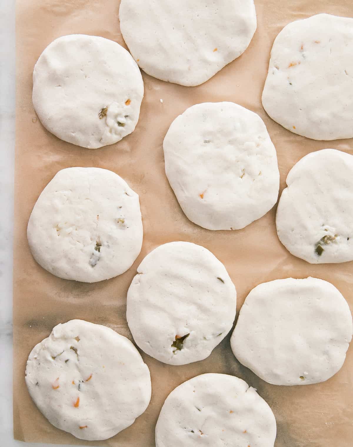 Formed uncooked pupusas on a piece of parchment