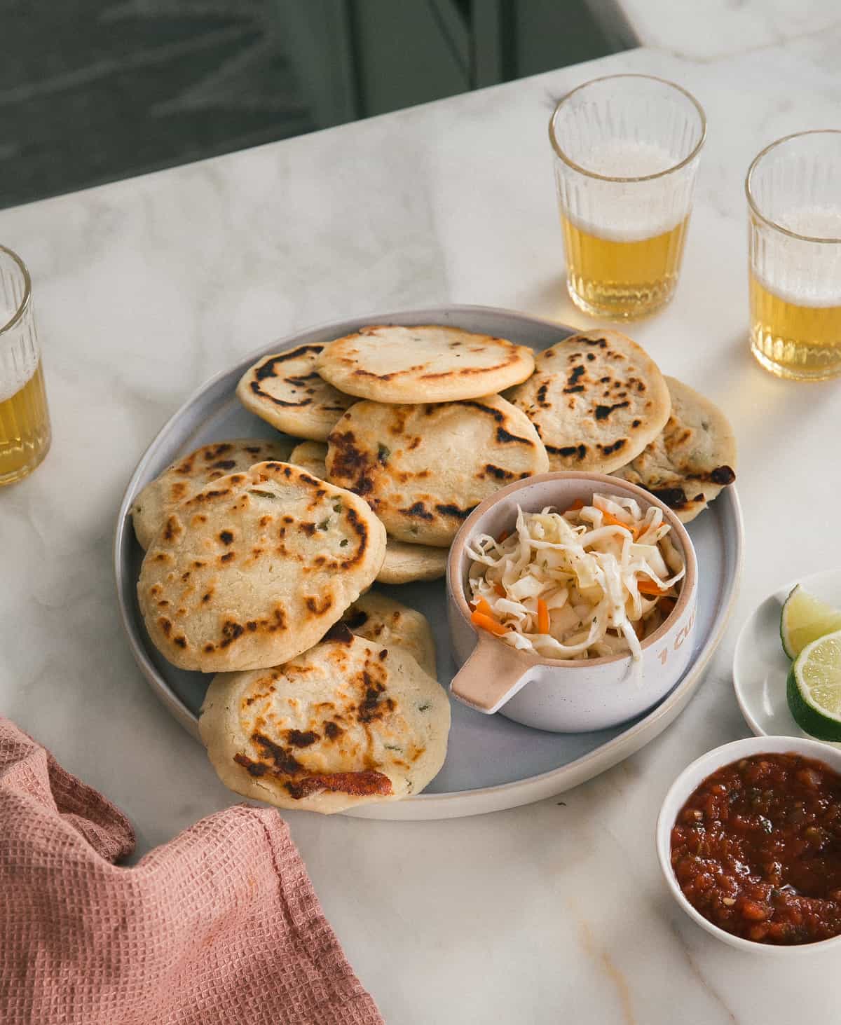 Pupusas on a plate surrounded by beer 