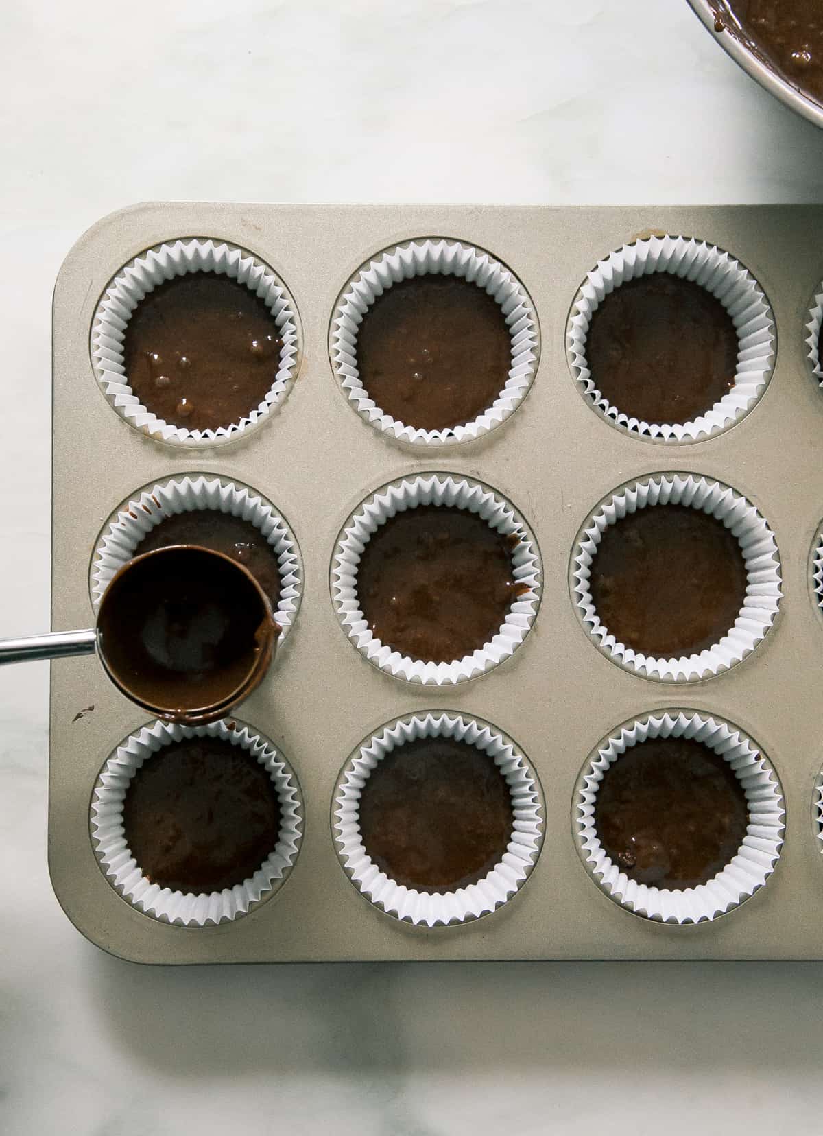 Batter being added to muffin tin. 