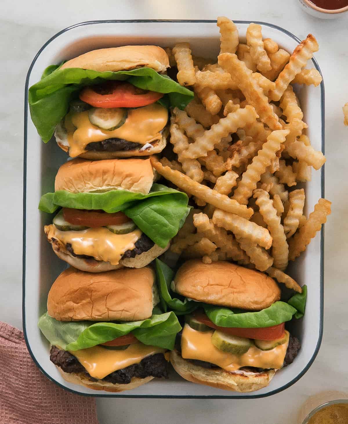 Burgers in a container with crinkle fries.
